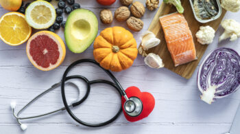 Stethoscope hiding a heart surrounded by healthy food: fruit, vegetables, fish. Healthy food concept to prevent diseases infiammazione